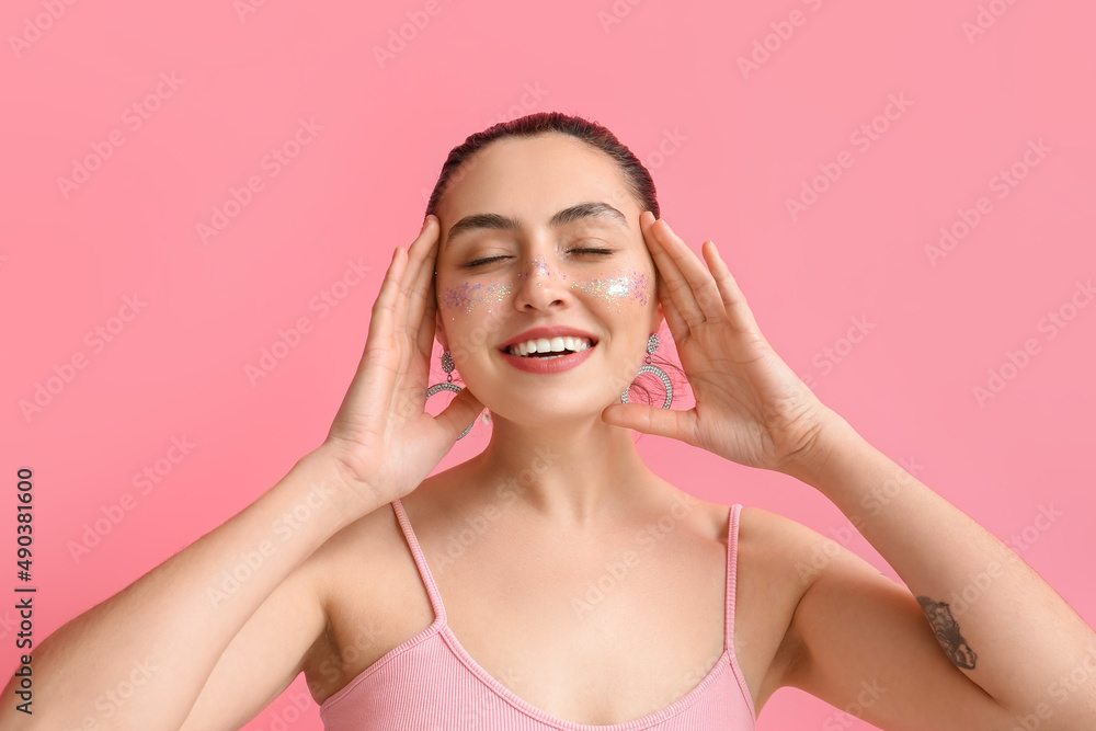 Smiling woman with creative makeup and closed eyes on pink background