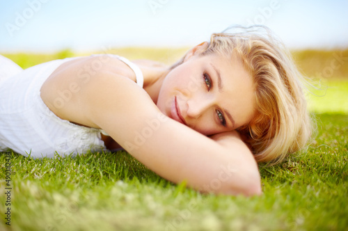 Taking her beauty outdoors. Portrait of a pretty young woman relaxed on a grass patch.