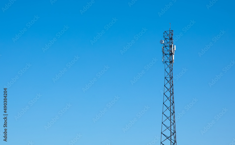 Wieża telekomunikacyjna na tle niebieskiego nieba - obrazy, fototapety, plakaty 