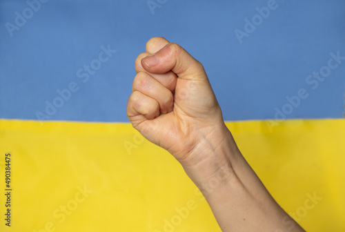 A female fist on the background of the national flag of Ukraine, the strength and anger of a Ukrainian woman against Russia, the war in Ukraine, we are invincible 2022