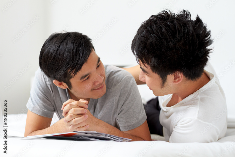 Living and loving together. Cute young gay Asian couple smiling while relaxing at home together. Living and loving together. Cute young gay Asian couple smiling while relaxing at home together.