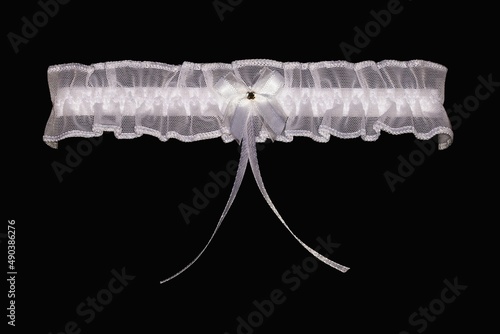 Schilderij op canvas Women's wedding white garter on a black background.