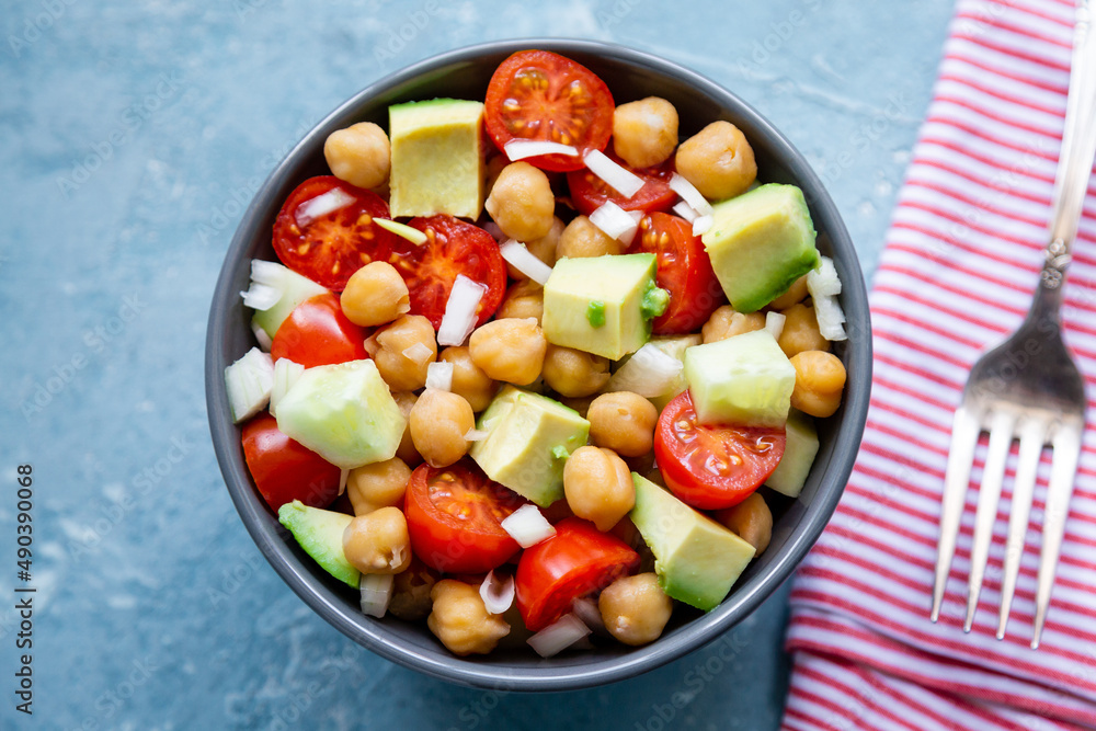 Top view of a bowl of chickpea salad with cherry tomato, avocado and cucumber
