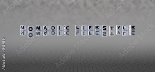 nomadic lifestyle word or concept represented by black and white letter cubes on a grey horizon background stretching to infinity