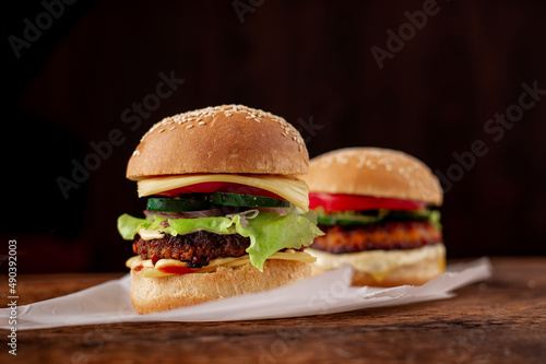 Two hamburgers on a wooden background. Big and small cheeseburger. Hamburger day.