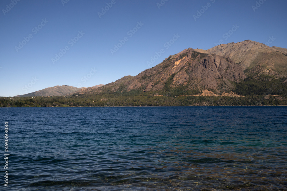 View of the turquoise water lake and the mountains in the background, in a sunny summer day. 