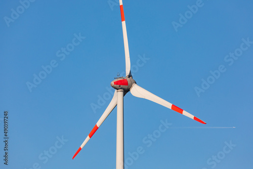 Nahaufnahme eines dreiblättrigen Propellers eines Windrades einer Windkraftanlage bei blauem Himmel