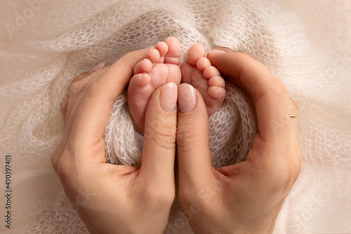 Mother is doing massage on her baby foot. Closeup baby feet in mother hands. Prevention of flat feet, development, muscle tone, dysplasia. Family, love, care, and health concepts. Studio macro.