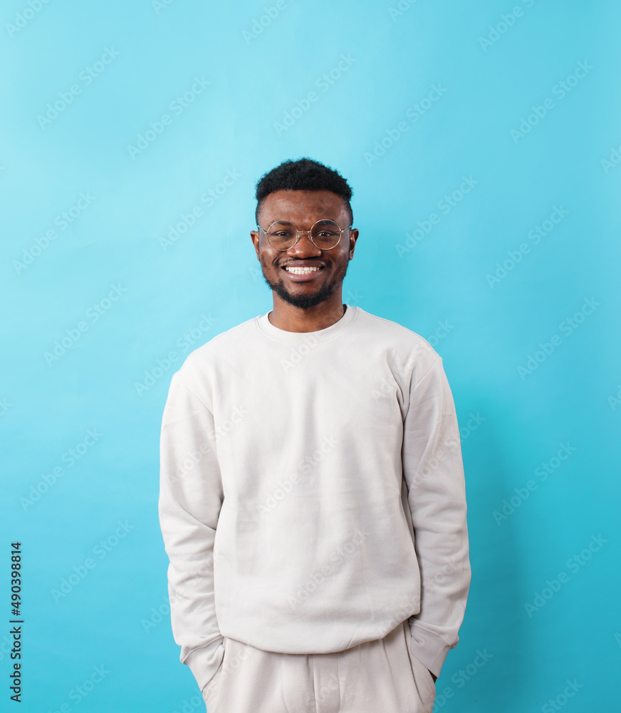 A young African-American man in a white T-shirt laughs on a blue isolated background A young African-American man in a white T-shirt laughs on a blue isolated background