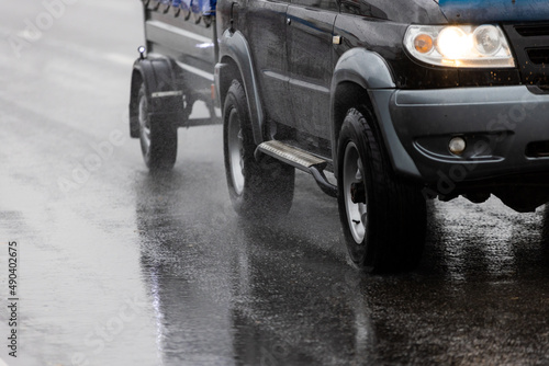 black offroad car with hindcarriage behind on wet asphalt road at rainy day photo