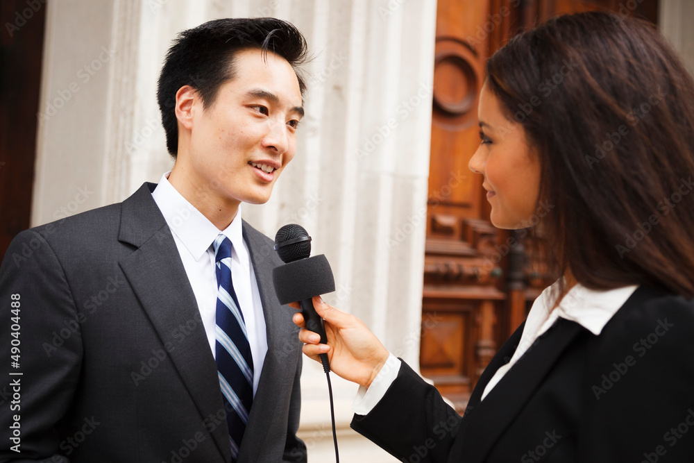 A woman with a microphone interviews a well dressed man. Could be politician, business or other professional. A woman with a microphone interviews a well dressed man. Could be politician, business or other professional.