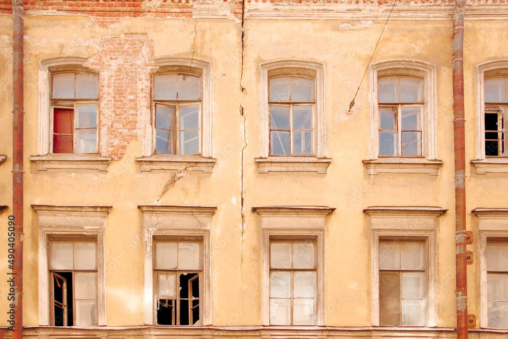 Facade of an old house with broken windows and a crack in the wall