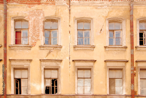 Facade of an old house with broken windows and a crack in the wall
