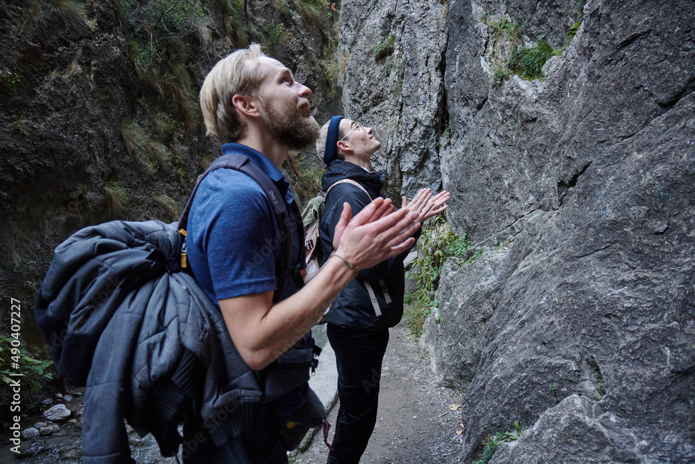 The Caucasian male hikers clapping on narrow path by the cliff