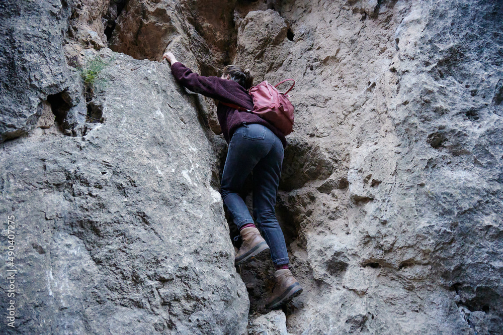 A Caucasian female hiker climbing up the rocky cliff