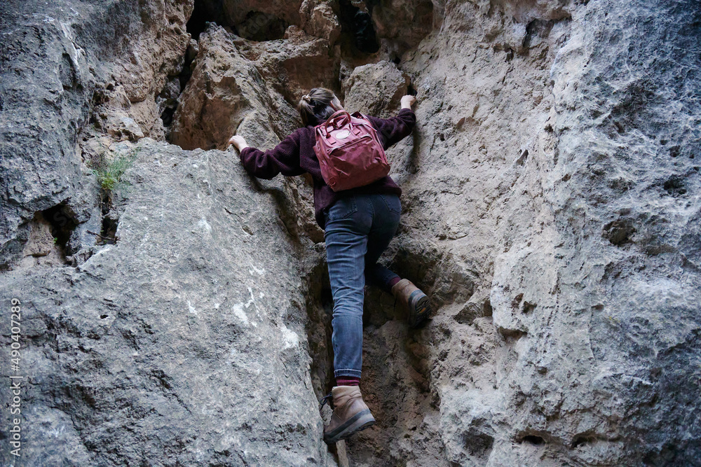 A Caucasian female hiker climbing up the rocky cliff A Caucasian female hiker climbing up the rocky cliff