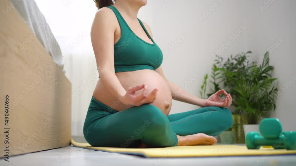 A pregnant woman is exercising with breath. Concept of a healthy lifestyle during pregnancy. Sports activities before the birth of baby. Useful exercises, fitness for health of the expectant mother A pregnant woman is exercising with breath. Concept of a healthy lifestyle during pregnancy. Sports activities before the birth of baby. Useful exercises, fitness for health of the expectant mother