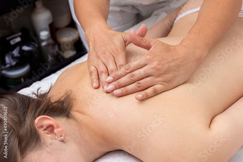 Massage session for a young woman  relaxing and harmonics in a beauty center with balls  algae  aromatic oils and reiki stones  performed by a beautician.