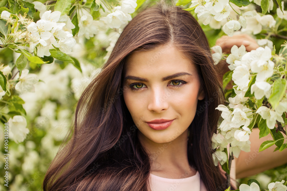 Romantic woman with perfect windy brown hair in spring flowers garden Romantic woman with perfect windy brown hair in spring flowers garden