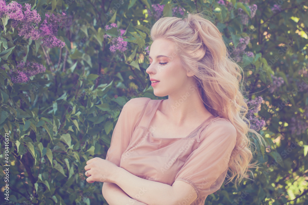 Pretty young woman with long healthy blonde hair on lilac flowers background, portrait Pretty young woman with long healthy blonde hair on lilac flowers background, portrait