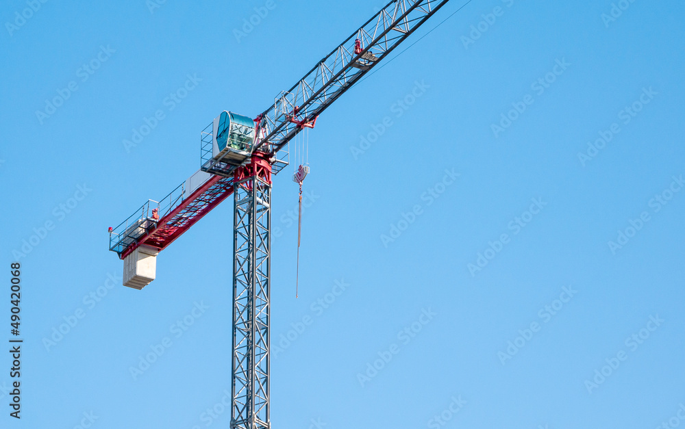 One single simple minimal industrial construction crane object isolated on blue clear sky background, nobody, no people, construction site industry business symbol, abstract concept
