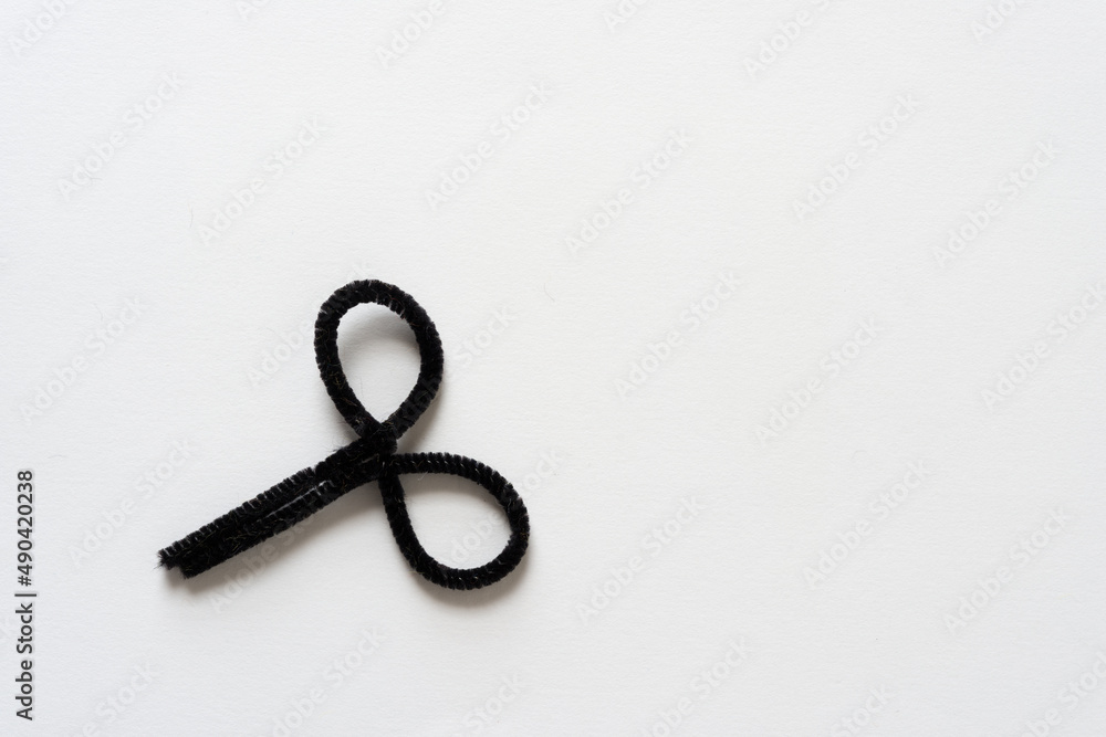 black pipe cleaner with two loops on a light background