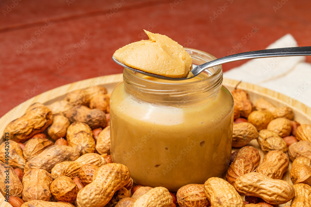 Peanut butter with group of peanuts inside a snack board on the wooden table Peanut butter with group of peanuts inside a snack board on the wooden table