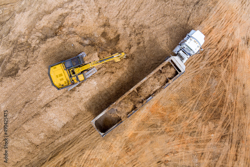 Aerial view at excavator and trucks working on the excavation works of a road, moving earth it onto the dump truck