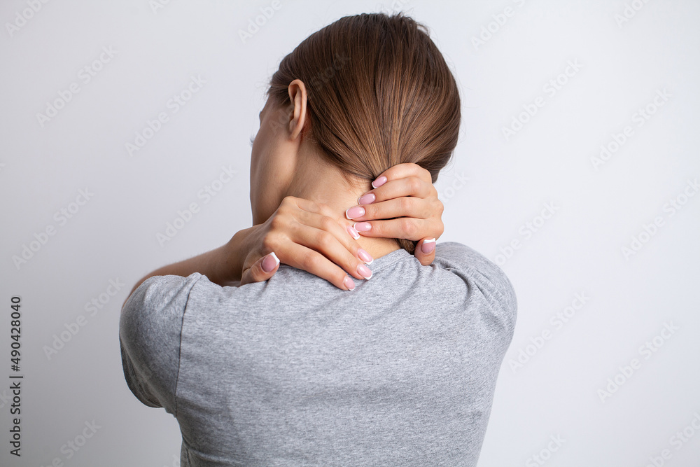 Sick woman suffering from sore neck on gray background Sick woman suffering from sore neck on gray background