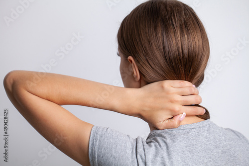 Sick woman suffering from sore neck on gray background
