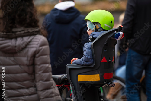 Portrait of little boy toddler with security helmet on the head sitting in bicycle seat. Safe and child protection concept.