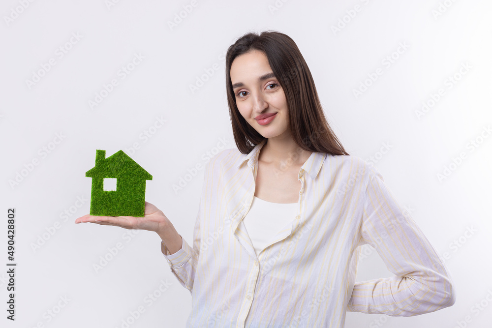 A young girl realtor holds a model of a green house in her hands. Sale of ecological real estate. A young girl realtor holds a model of a green house in her hands. Sale of ecological real estate.