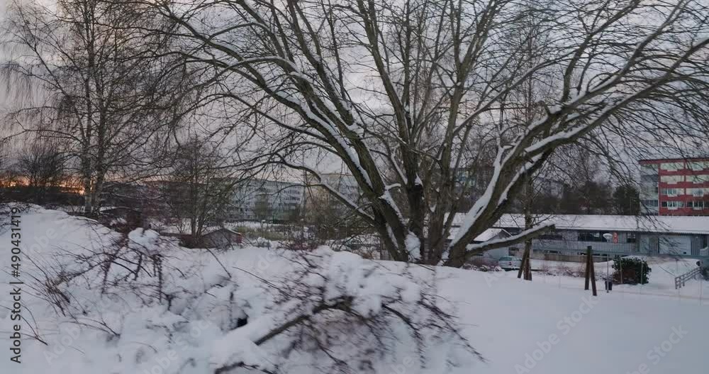 POV Walking by a Playground and Parking Garage in an Apartment Neighbourhood in a Snowy Winter in Borås, Sweden - Wide Shot Tracking Sideways POV Walking by a Playground and Parking Garage in an Apartment Neighbourhood in a Snowy Winter in Borås, Sweden - Wide Shot Tracking Sideways