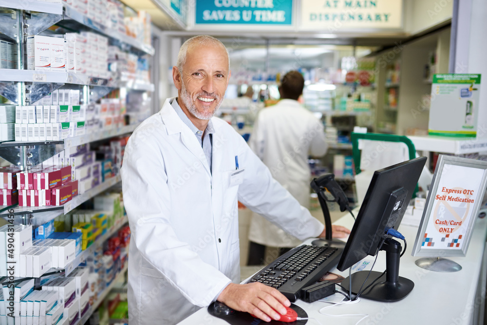 Here to help keep you in your best health. Portrait of a mature pharmacist working on a computer in a chemist.