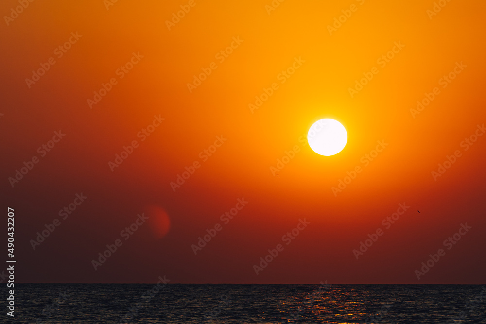 Dramatic vibrant sun over ocean with lens flare