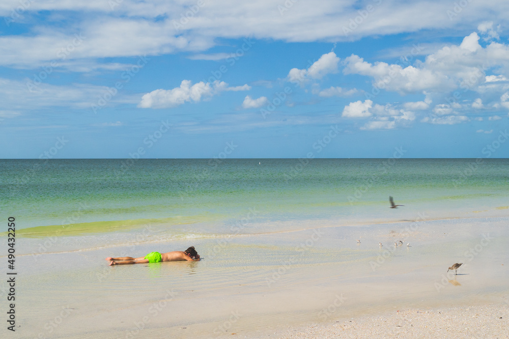 Kids lying face down in water on beach