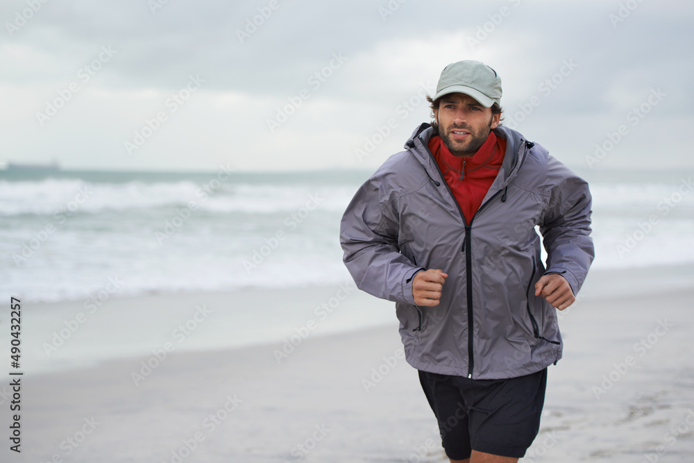 Taking a morning run on the beach. Cropped shot of a handsome young man running on the beach. Taking a morning run on the beach. Cropped shot of a handsome young man running on the beach.
