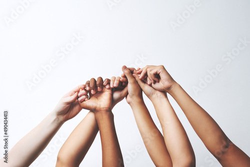 Let your hands do the talking. Studio shot of a group of unrecognizable people holding each others thumbs while their hands are raised.
