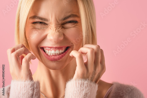 Canvas Print close up of blonde woman frowning and grinning isolated on pink.