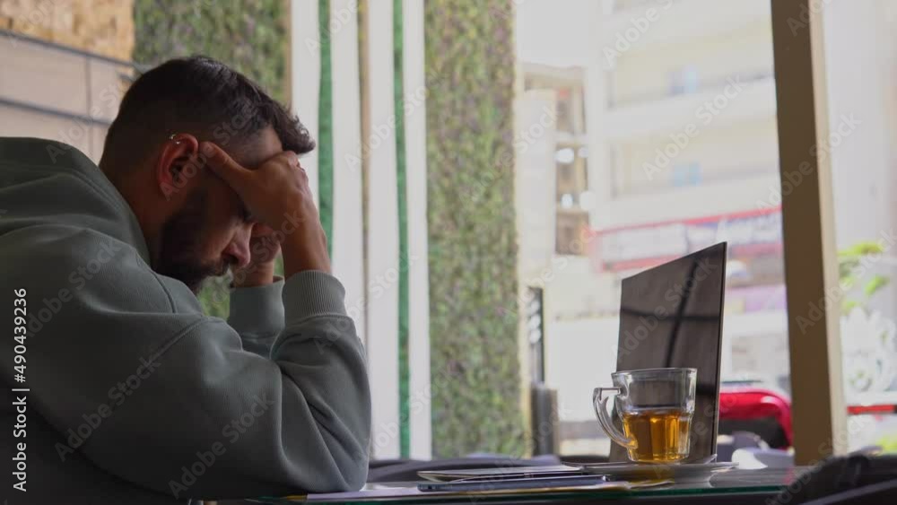 Disappointed Creative Man Feeling Worried during working with laptop in modern cafe. Working burnout concept Disappointed Creative Man Feeling Worried during working with laptop in modern cafe. Working burnout concept