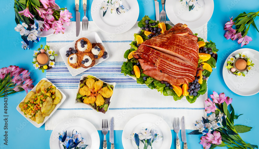 Festive Easter table with ham, salad and pancakes.