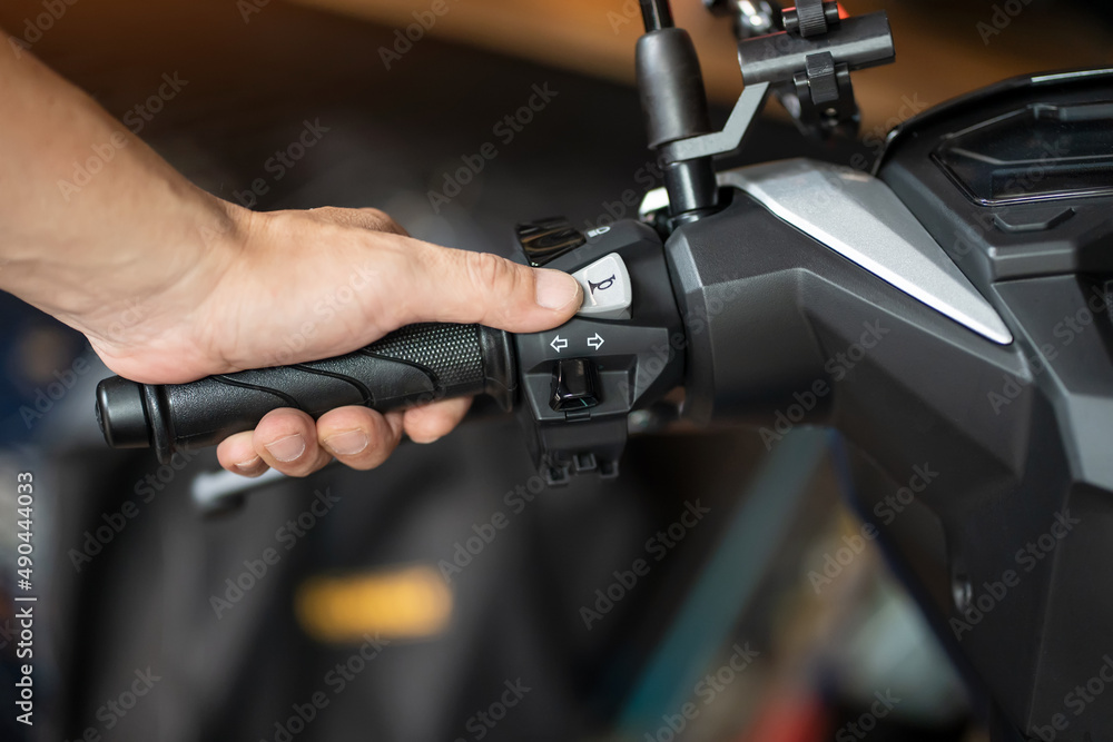 rider holding handlebar and pressing the horn button on motorcycle, repair motorcycle concept in garage.selective focus