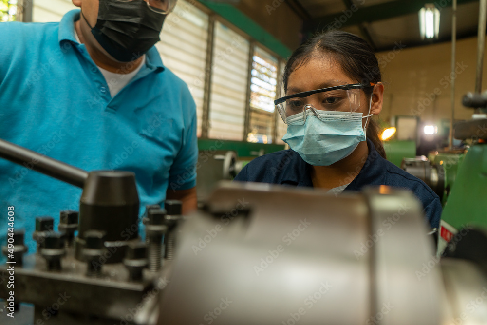 Latin young woman working on an industrial lathe as a symbol of female empowerment Latin young woman working on an industrial lathe as a symbol of female empowerment