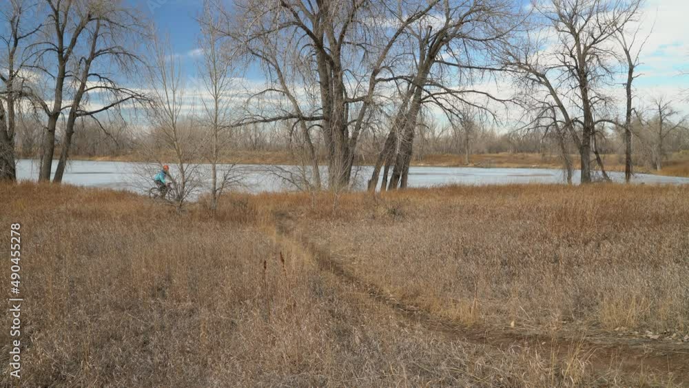 senior male cyclist is riding a gravel bike on a single track trail in winter or fall scenery - Arapaho Bend Natural Area in Fort Collins, Colorado senior male cyclist is riding a gravel bike on a single track trail in winter or fall scenery - Arapaho Bend Natural Area in Fort Collins, Colorado