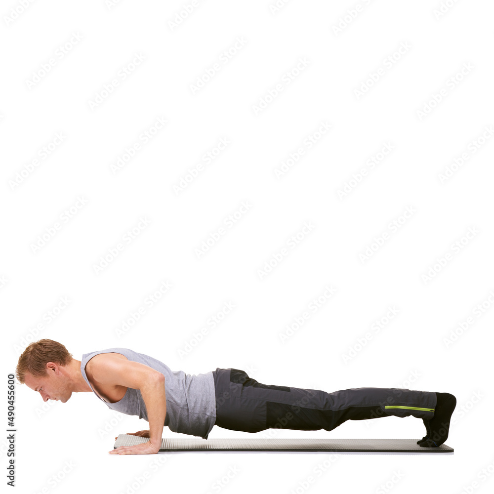 Determined to reach his fitness goals. A fit young man doing push-ups on his exercise mat while isolated on white. Determined to reach his fitness goals. A fit young man doing push-ups on his exercise mat while isolated on white.