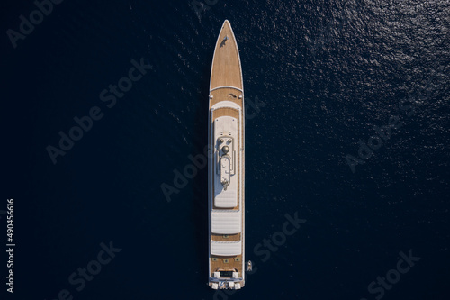 Big yacht for millionaires in the sea drone view. Big white super ship in the dark ocean aerial view. Luxurious white mega yacht on dark water in the reflection of the sun top view.