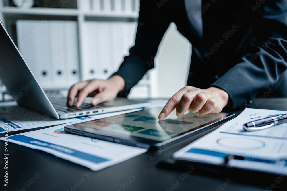Close up of Businesswomen or Accountant using a digital tablet and laptop computer analytic business report graph and finance chart at the workplace, financial and investment concept. Close up of Businesswomen or Accountant using a digital tablet and laptop computer analytic business report graph and finance chart at the workplace, financial and investment concept.
