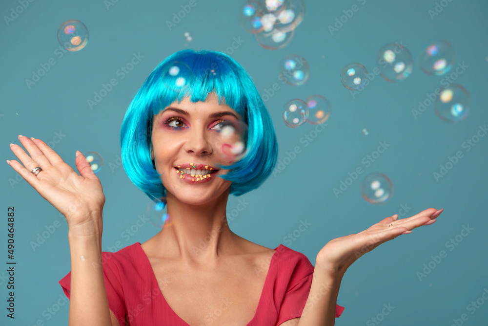 Beautiful young woman with blue wig and bright make-up in soap bubbles. Fashion model girl with creative color makeup. Women doll concept. Beautiful young woman with blue wig and bright make-up in soap bubbles. Fashion model girl with creative color makeup. Women doll concept.