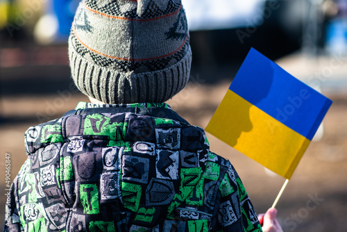 Obraz na plátně Child or kid with winter clothes, hat and Ukrainian flag, profile of the child is on the flag