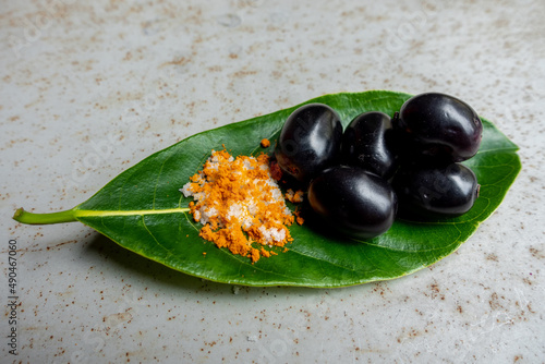 Spicy mixed salt with some black java plum fruit in the green leaves. A way to eat ripe cesium camini fruit by hand. 4k closeup video. photo